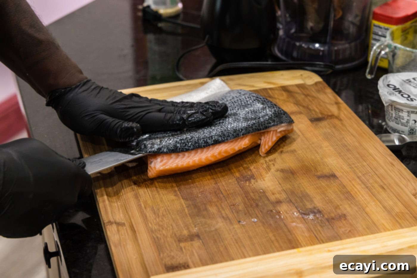Delicious Salmon Burgers 5 Removing skin from salmon with a chef knife on a cutting board