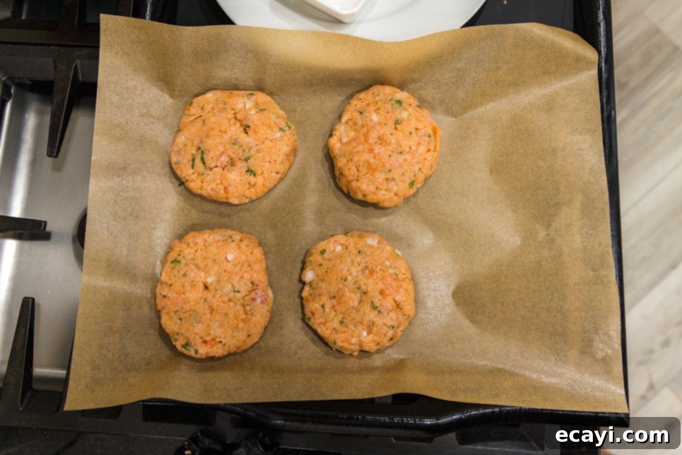 Delicious Salmon Burgers 10 Raw salmon patties laid out on parchment paper