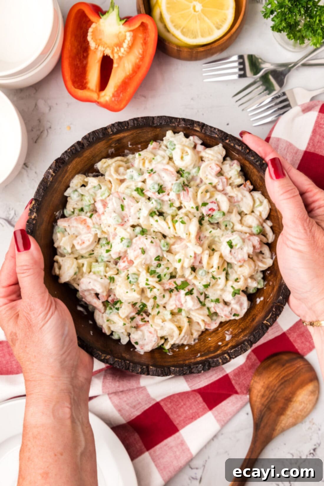 Lemon-Herb Shrimp Pasta Salad 2 Hands gently holding a rustic bowl filled with vibrant Shrimp Pasta Salad, garnished with fresh dill.