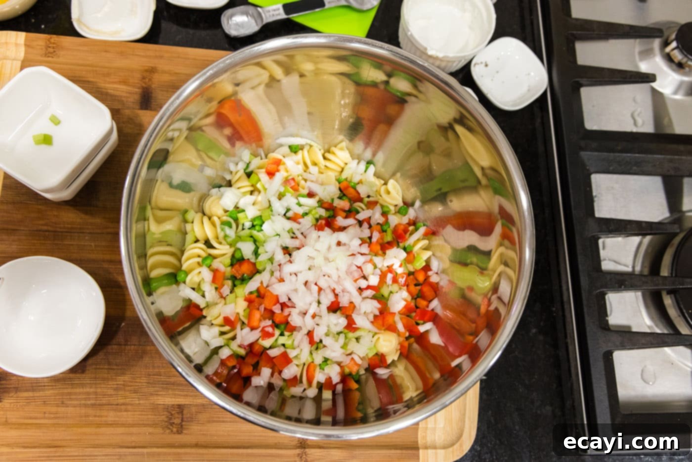 Lemon-Herb Shrimp Pasta Salad 7 Diced bell peppers and chopped onion are added to the rotini pasta and other vegetables in a large mixing bowl.
