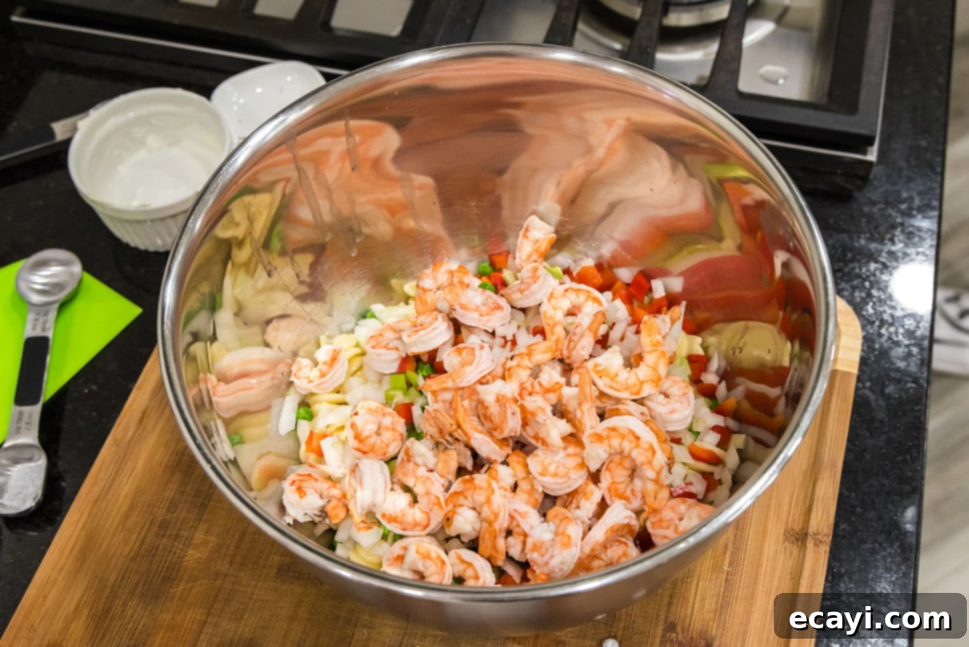 Lemon-Herb Shrimp Pasta Salad 8 Cooked shrimp being added to the large bowl containing pasta and a variety of fresh vegetables, ready for dressing.