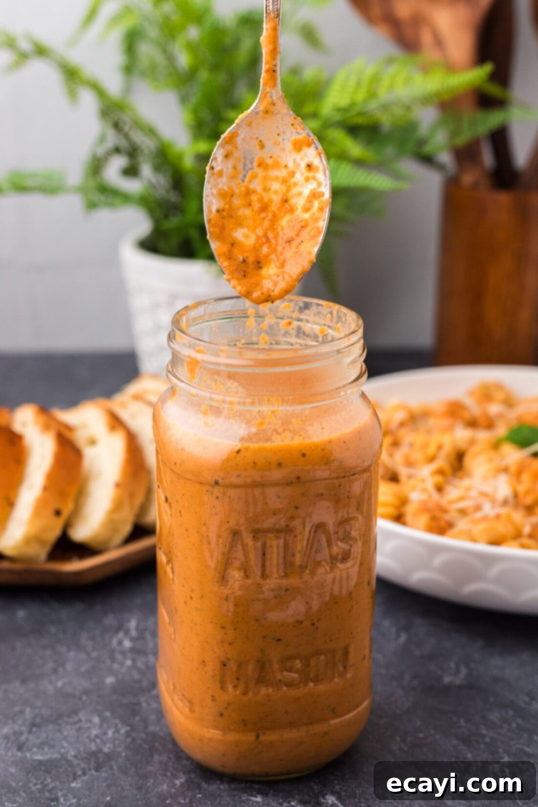Creamy Vodka Pasta Sauce 2 Spoon covered in Vodka Sauce being lifted out of a jar of Vodka Sauce, showcasing its rich, creamy texture and vibrant color.