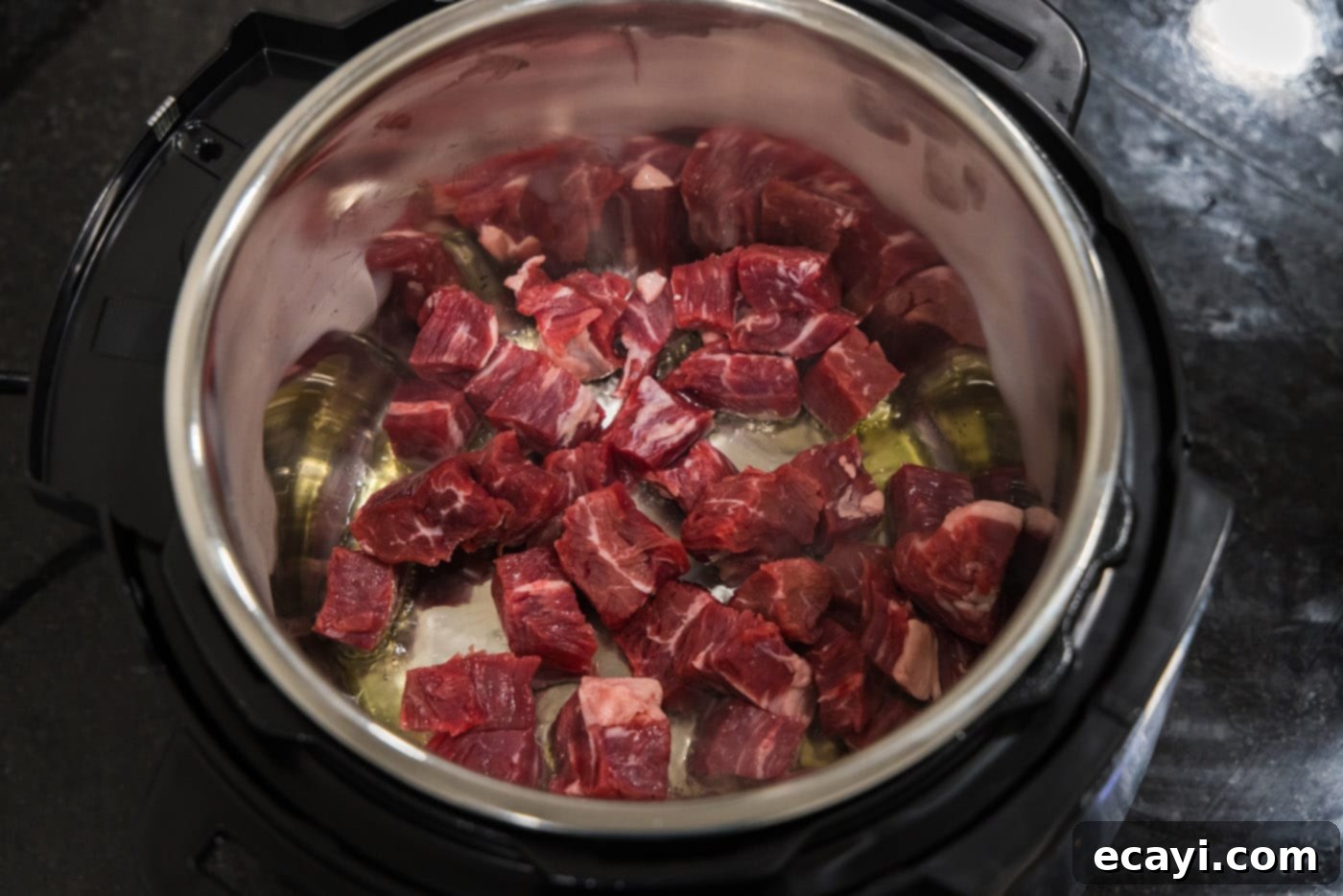 Delicious Instant Pot Beef and Broccoli 7 Flank steak cubes actively browning in hot olive oil within an Instant Pot set to sauté mode, showing a perfect sear.