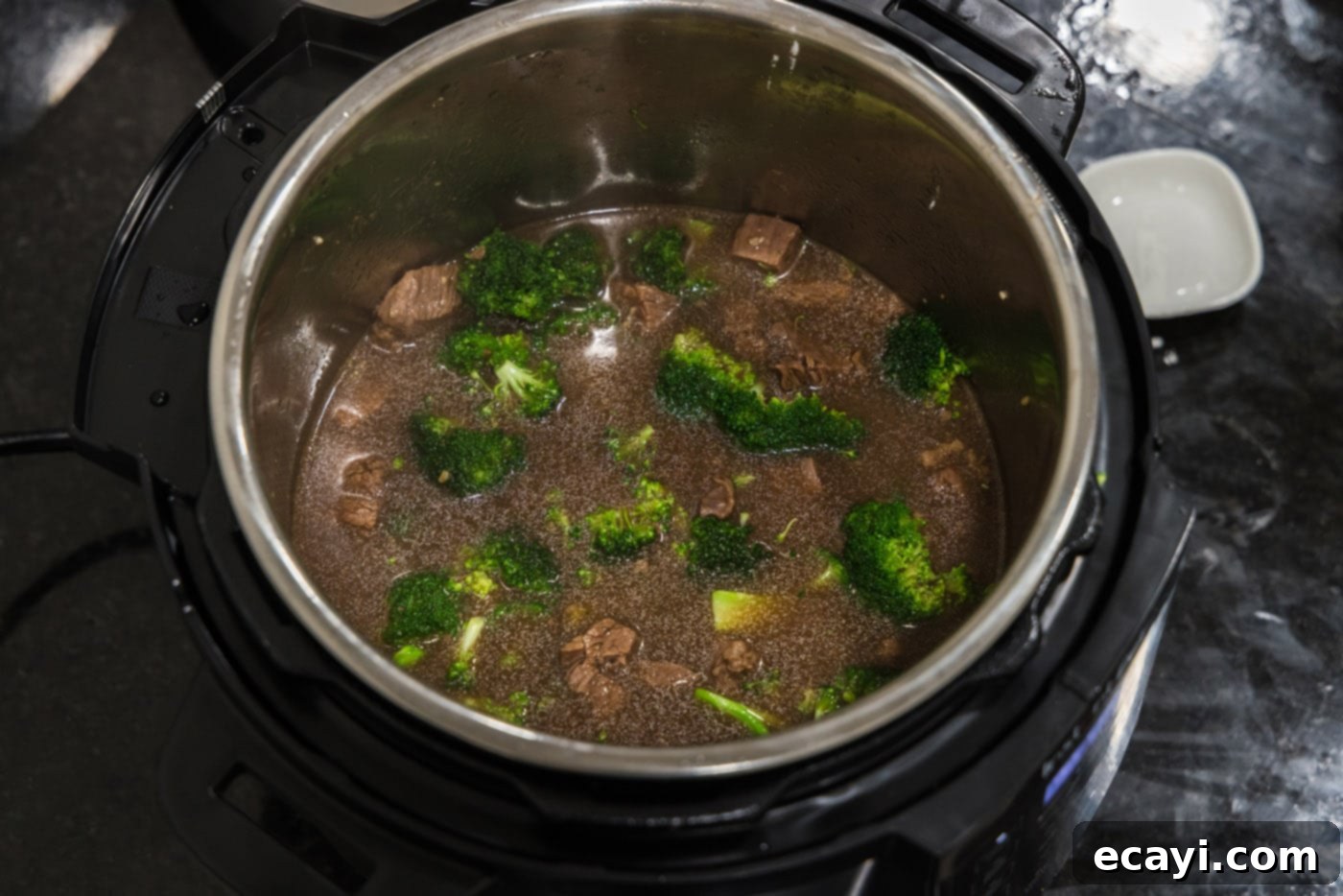 Delicious Instant Pot Beef and Broccoli 10 The delicious beef and broccoli mixture simmering in the Instant Pot, with the sauce beginning to thicken and the broccoli turning bright green.