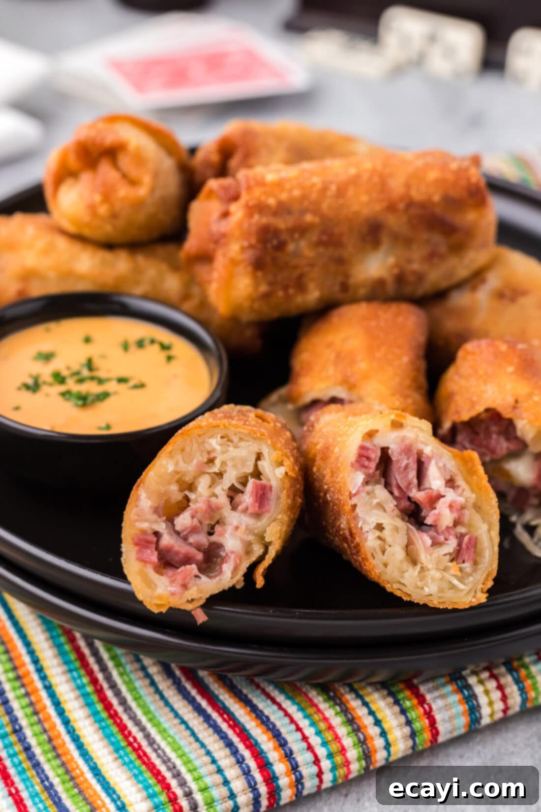 Crispy Reuben Egg Rolls 2 Close up photo of golden brown Reuben Egg Rolls on a plate, ready to be dipped, with a bowl of Thousand Island dressing beside them.