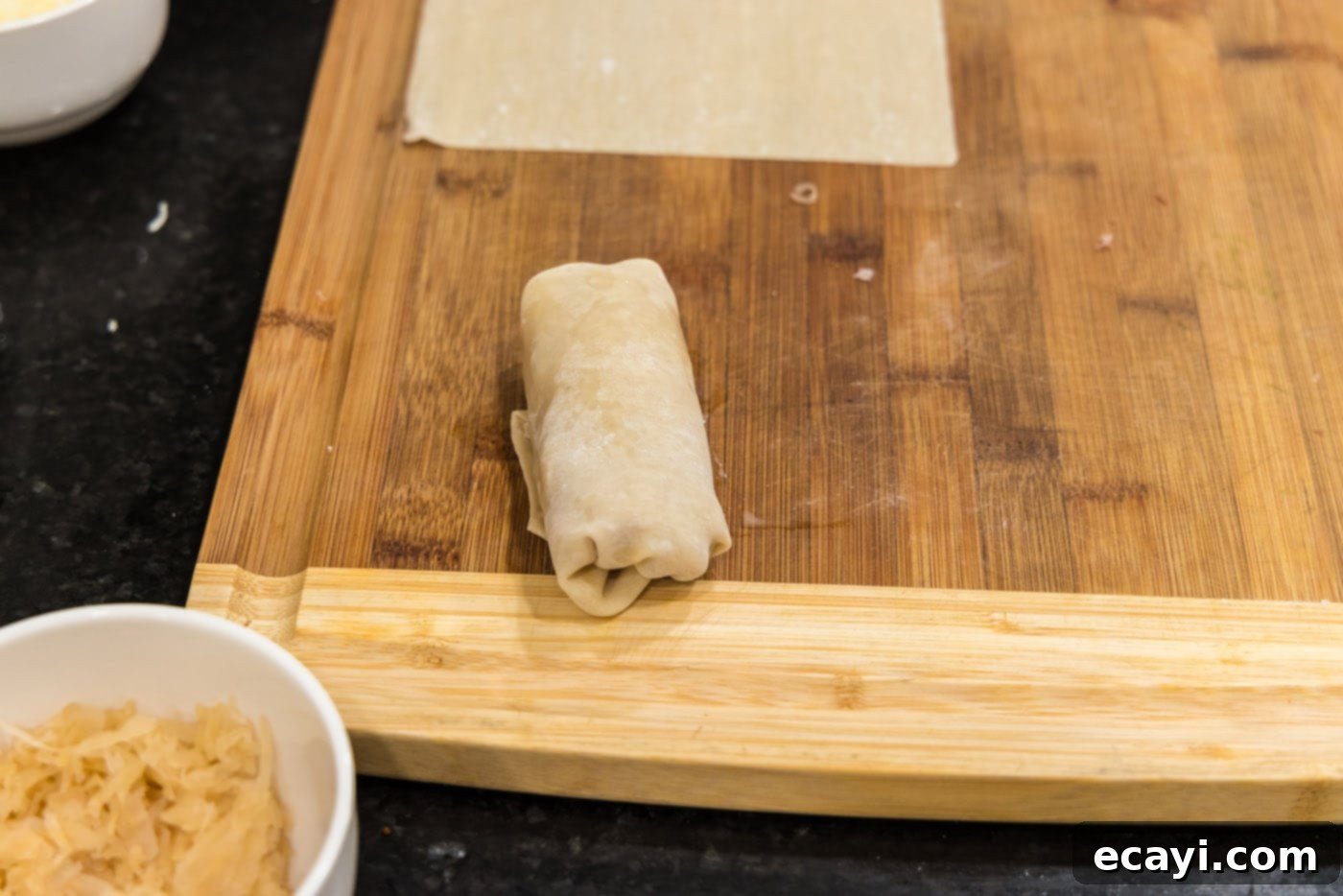 Crispy Reuben Egg Rolls 11 Several neatly rolled Reuben egg rolls lined up on a cutting board, ready for deep frying.