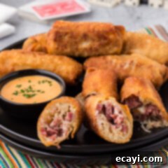 Crispy Reuben Egg Rolls 15 Close up photo of a Reuben Egg Roll cut in half on a plate with more rolls in the background