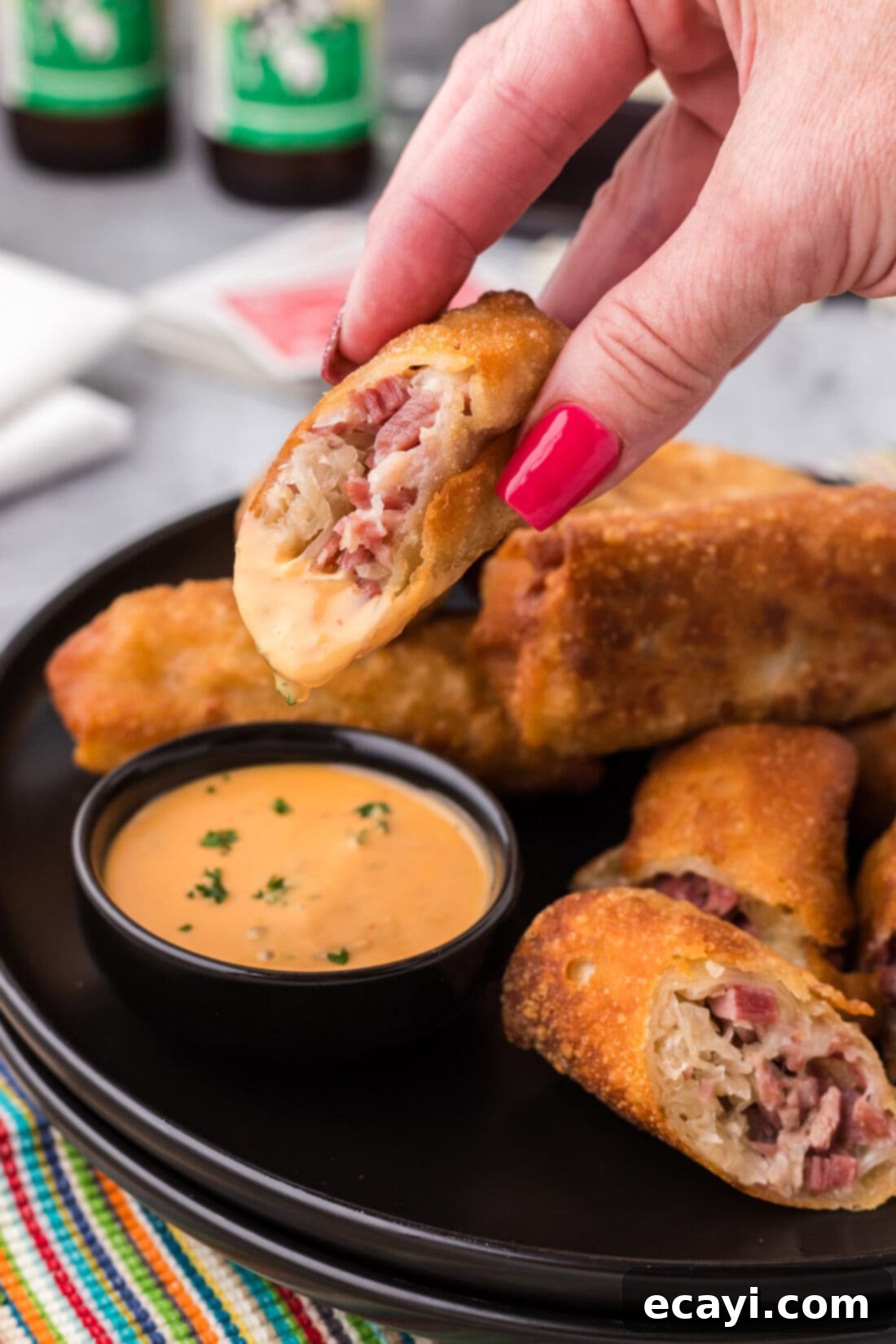 Crispy Reuben Egg Rolls 3 A perfectly fried Reuben Egg Roll cut in half, showcasing its cheesy, corned beef, and sauerkraut filling, being dipped into creamy Thousand Island dressing.