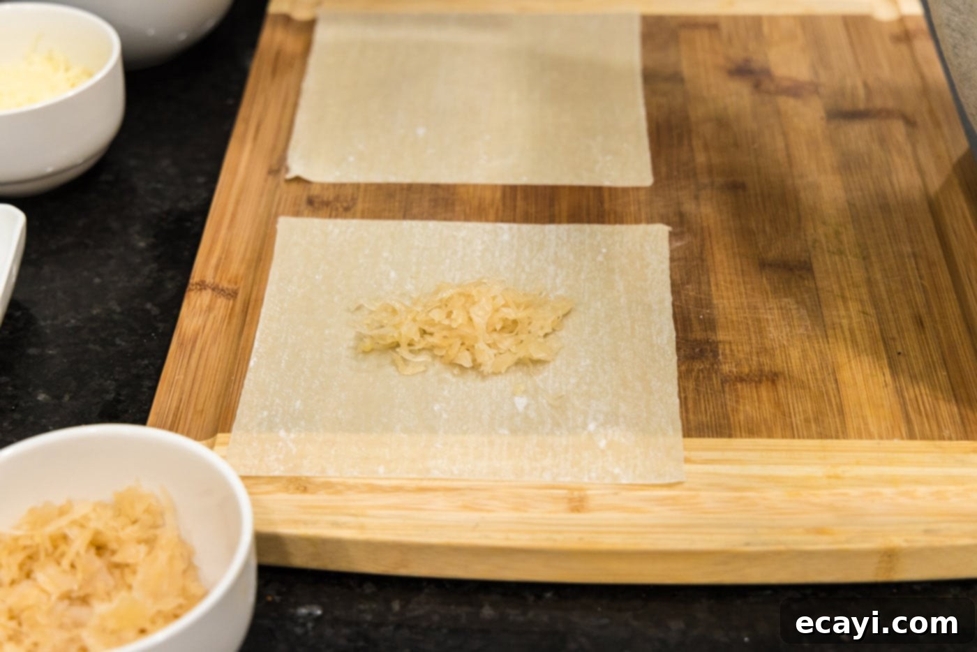 Crispy Reuben Egg Rolls 5 A small mound of thoroughly drained sauerkraut placed in the center of an egg roll wrapper on a cutting board.
