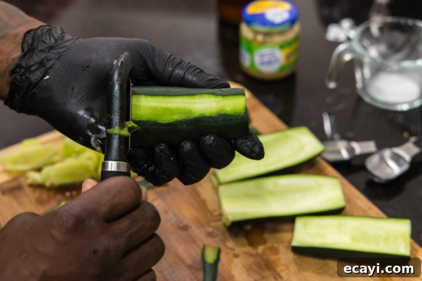 Chilled Lobster Cucumber Canoes 11 Demonstration of carefully removing a thin strip of skin from the underside of a hollowed-out cucumber half using a knife, to create a flat, stable base for the boat.