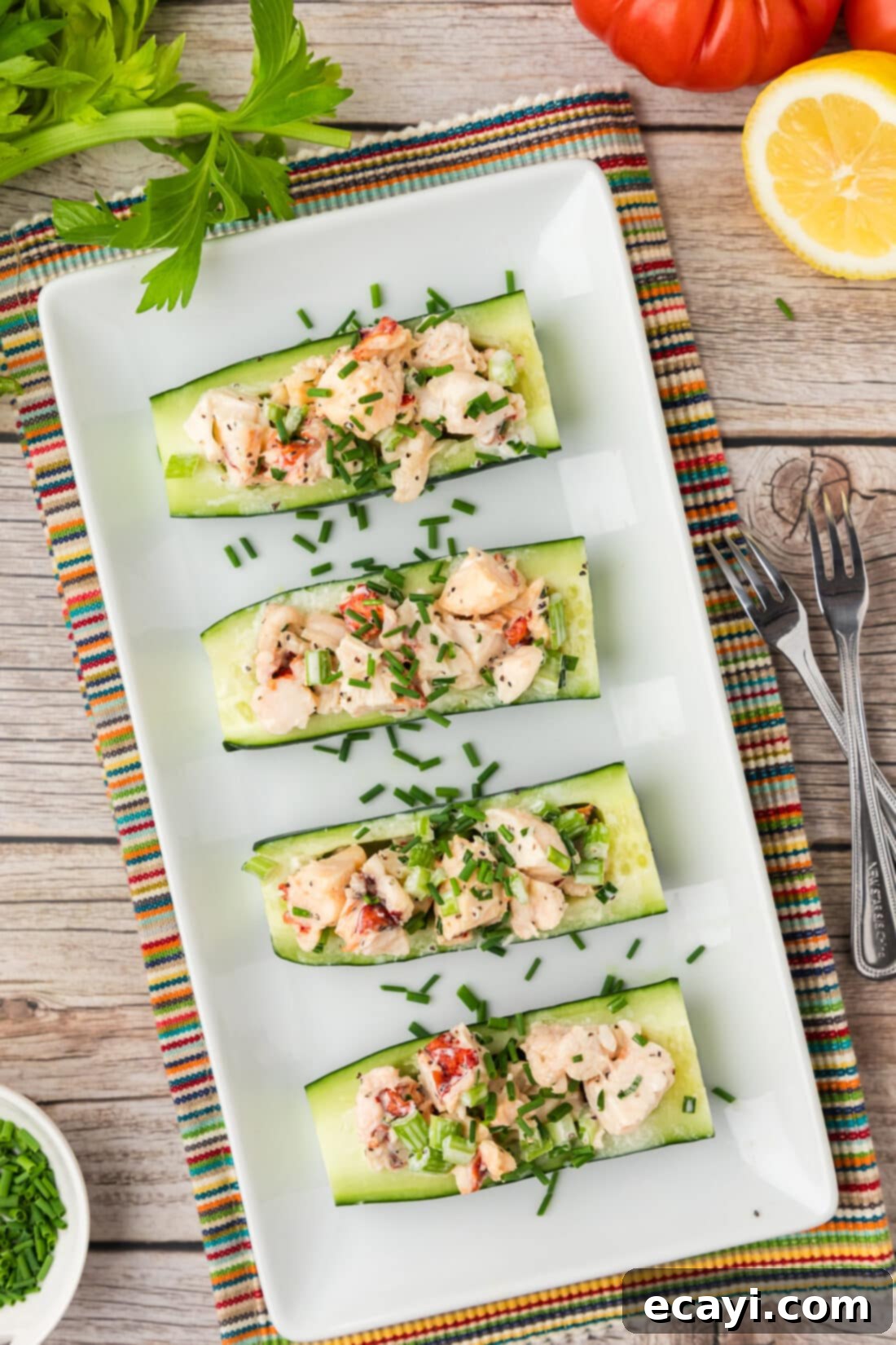 Chilled Lobster Cucumber Canoes 3 Overhead shot of beautifully arranged Lobster Cucumber Boats on an elegant white serving platter, garnished with fresh chives, ready to be enjoyed as an appetizer or light meal.