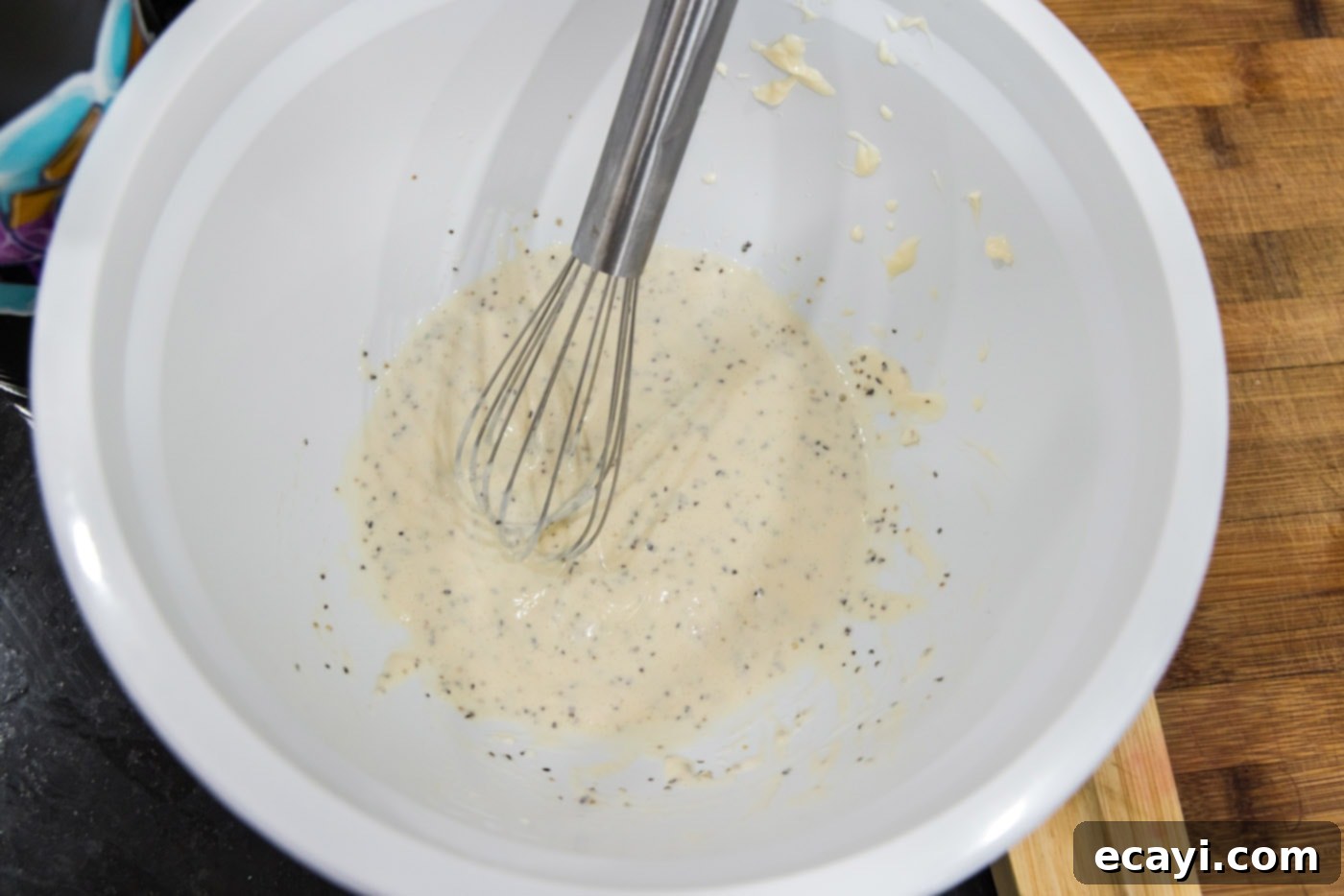Chilled Lobster Cucumber Canoes 5 All dressing ingredients for lobster salad, including mayonnaise, lemon juice, horseradish, salt, and pepper, are placed in a large mixing bowl with a whisk, showing a creamy, light-colored mixture being prepared.