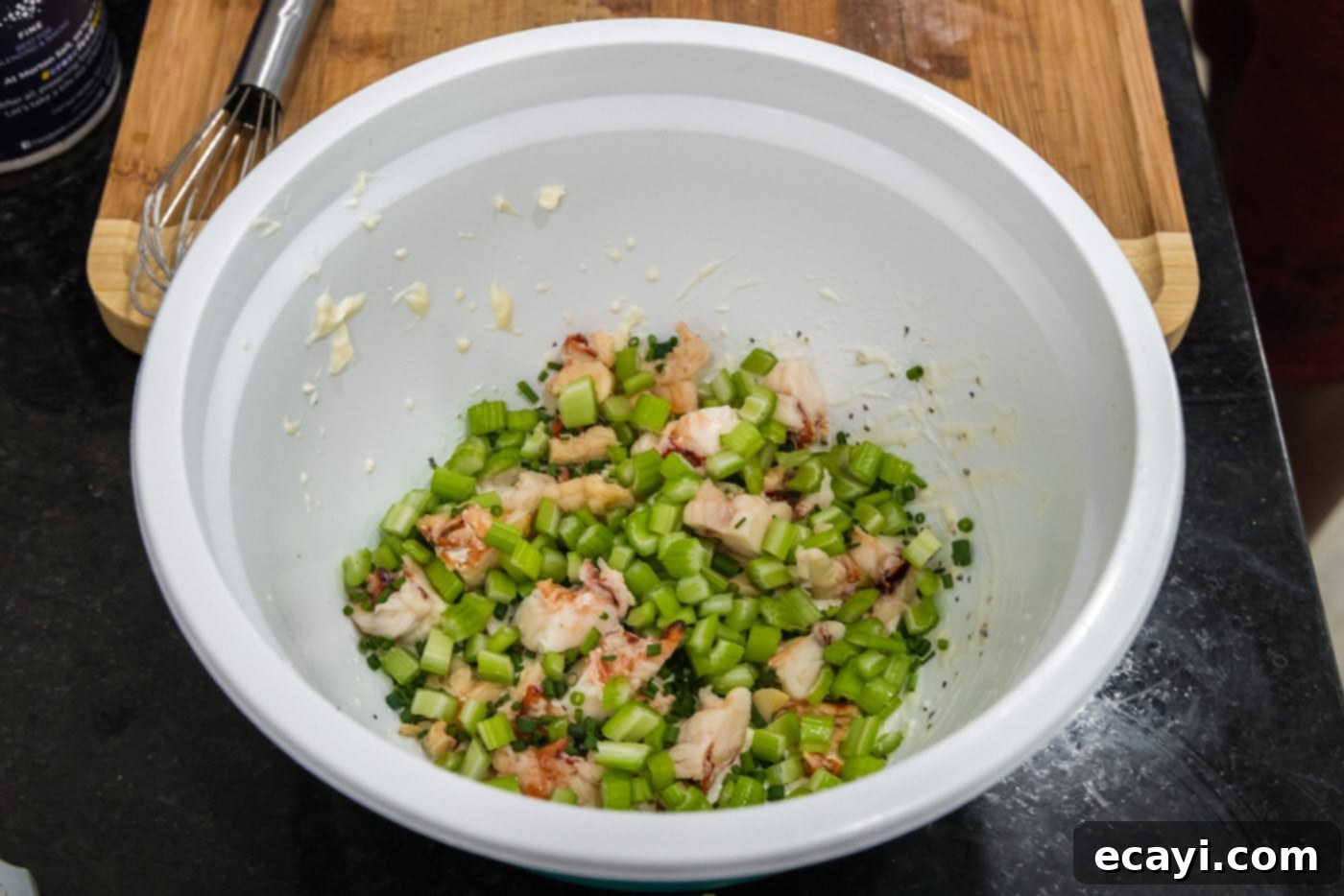 Chilled Lobster Cucumber Canoes 7 Freshly chopped chives and finely diced celery added to the mixing bowl alongside the creamy dressing and lobster meat, showcasing the vibrant, fresh ingredients before mixing.