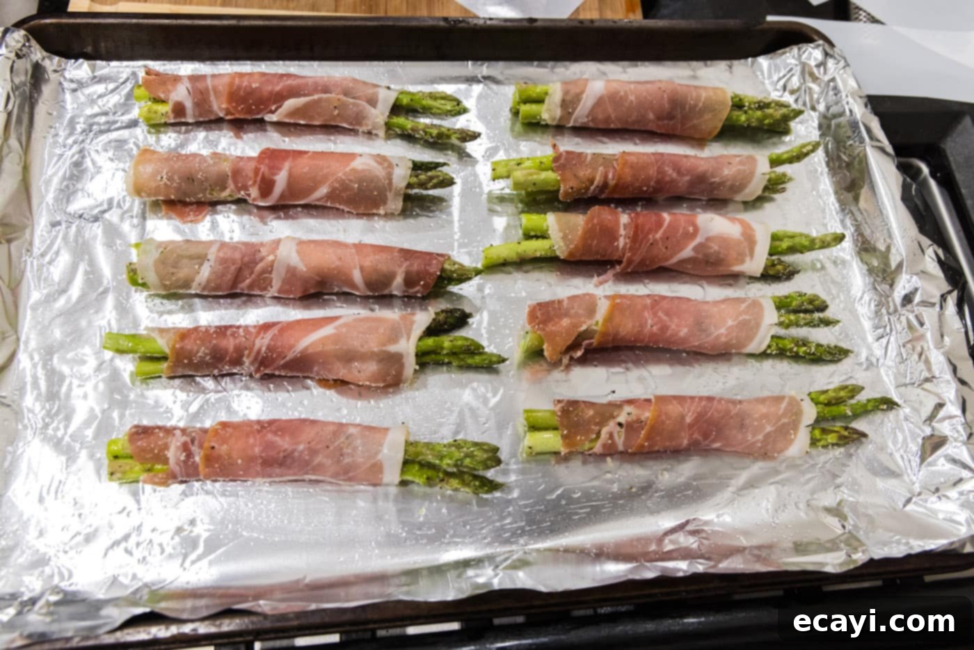Crispy Prosciutto-Wrapped Asparagus 12 prosciutto wrapped asparagus on a baking sheet