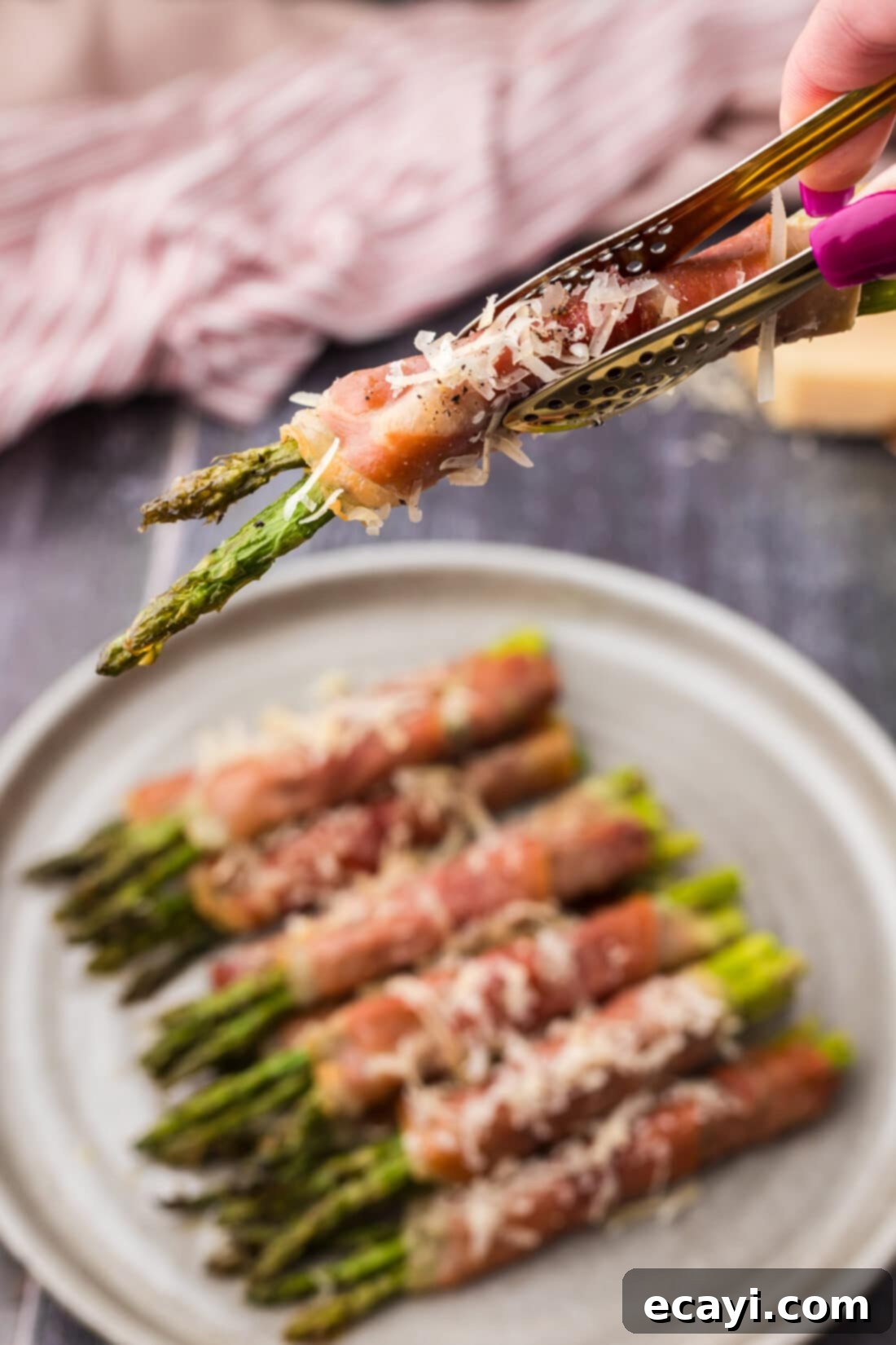 Crispy Prosciutto-Wrapped Asparagus 15 Tongs holding up Prosciutto Wrapped Asparagus