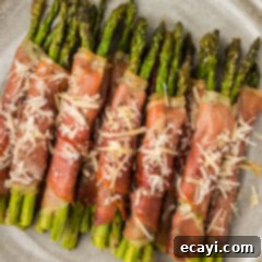Crispy Prosciutto-Wrapped Asparagus 16 Close up photo of Prosciutto Wrapped Asparagus on a plate topped with shaved parmesan