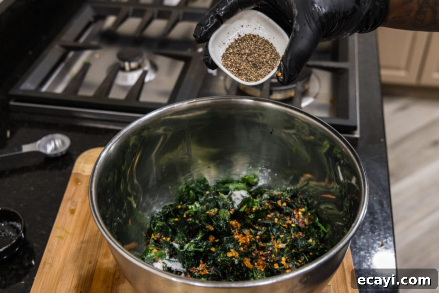 Crispy Spinach Sauté 11 Freshly ground black pepper being added to the fried spinach with red pepper flakes and garlic.
