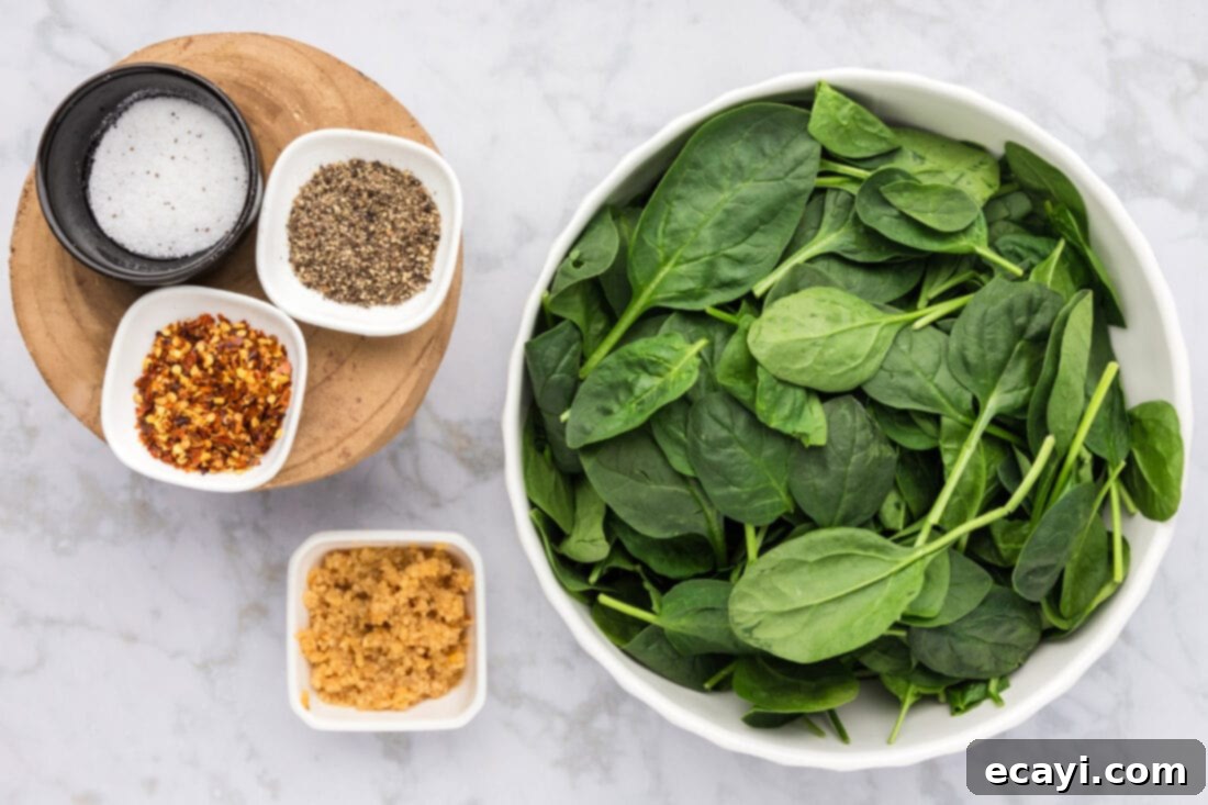 Crispy Spinach Sauté 4 A flat lay of fresh spinach, minced garlic, red pepper flakes, salt, and black pepper, the ingredients for fried spinach.