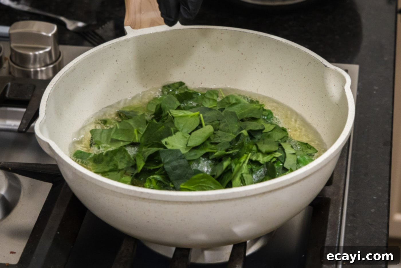 Crispy Spinach Sauté 5 Close up view of spinach leaves being dropped into hot oil for frying.