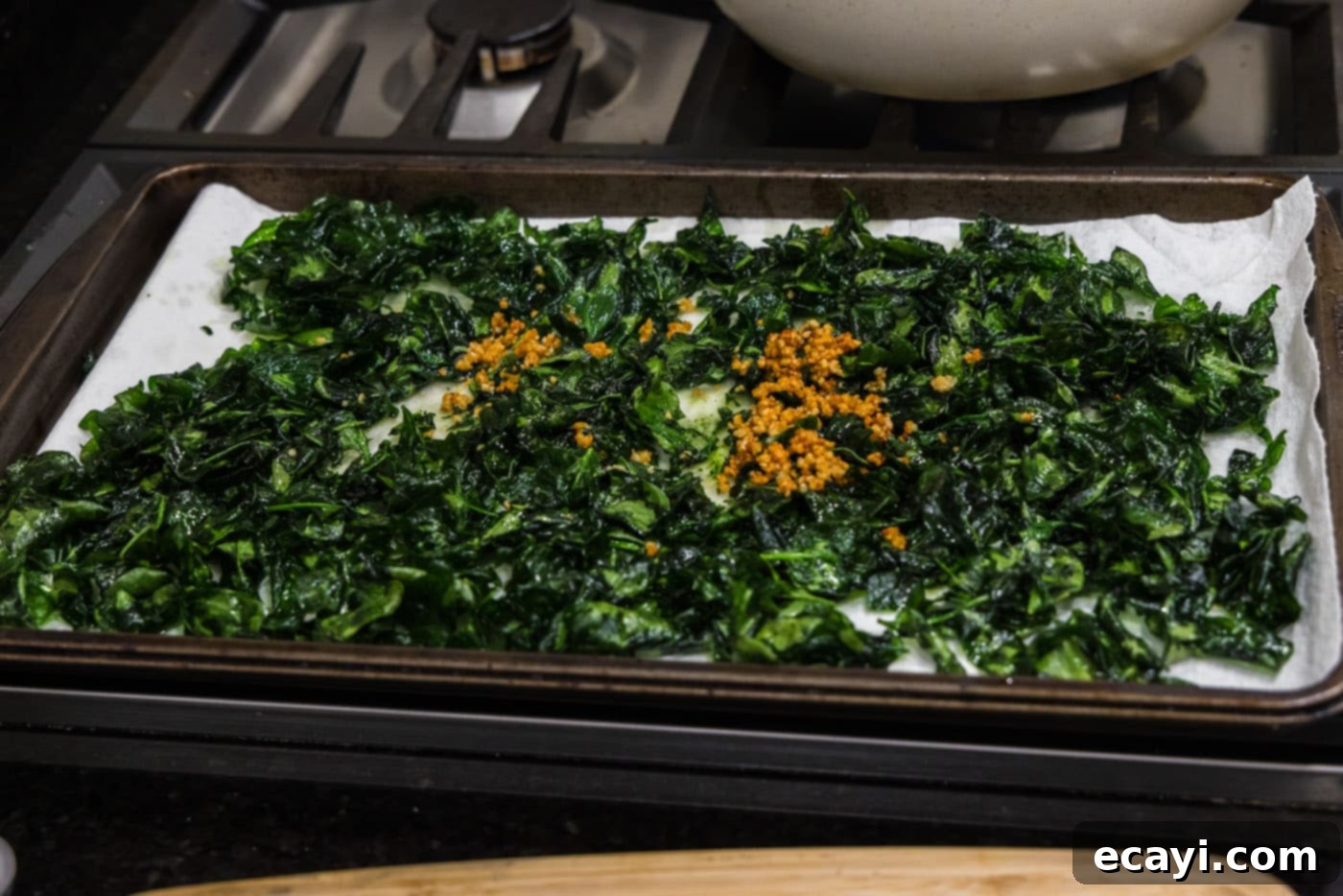 Crispy Spinach Sauté 9 Fried garlic being added on top of the already drained crispy fried spinach.