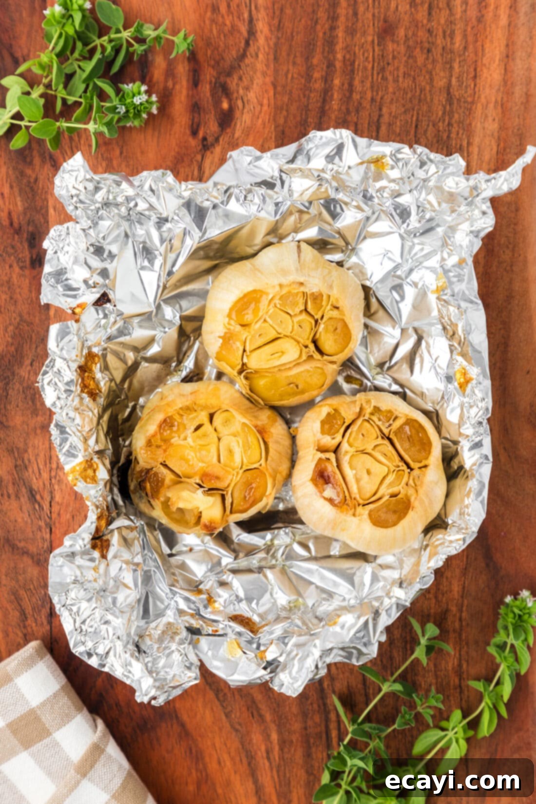Roasting Garlic Made Easy 2 Three bulbs of roasted garlic in foil on a wooden board