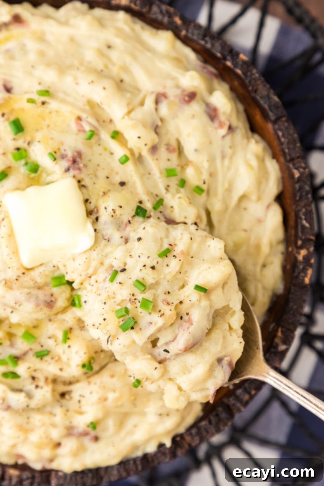 Creamy Garlic Mash 3 Close-up photo of a spoon scooping a fluffy portion of garlic mashed potatoes from a white bowl, highlighting the creamy texture and small flecks of roasted garlic.