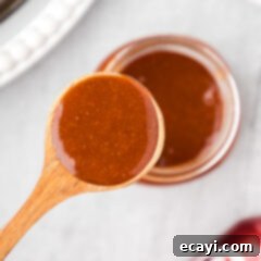Dr Pepper Infused BBQ Sauce 12 Close up photo of a spoon of Dr Pepper Barbecue Sauce held above a jar of Dr Pepper Barbecue Sauce