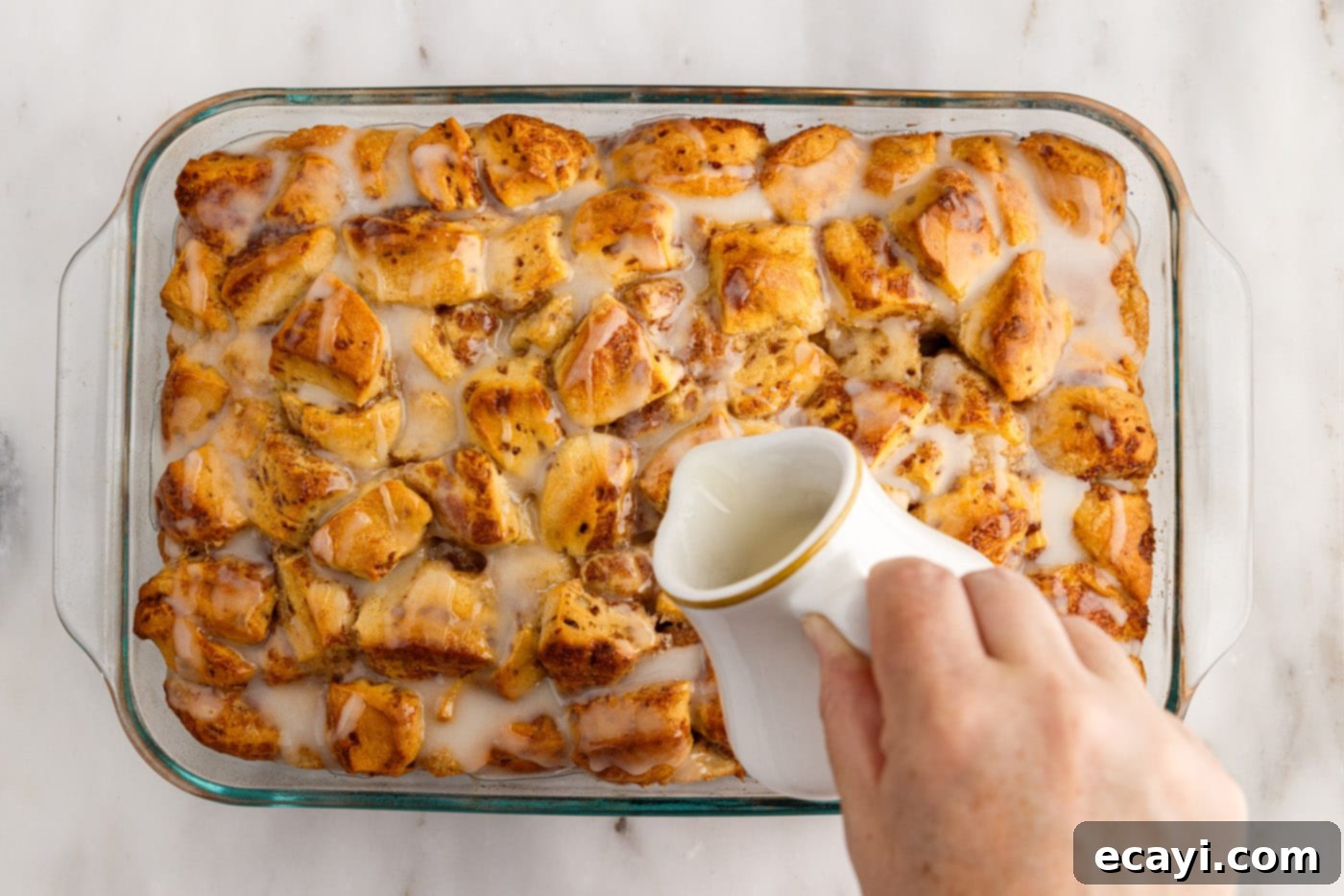 Gooey Cinnamon Brunch Bake 11 pouring icing over warm cinnamon roll casserole