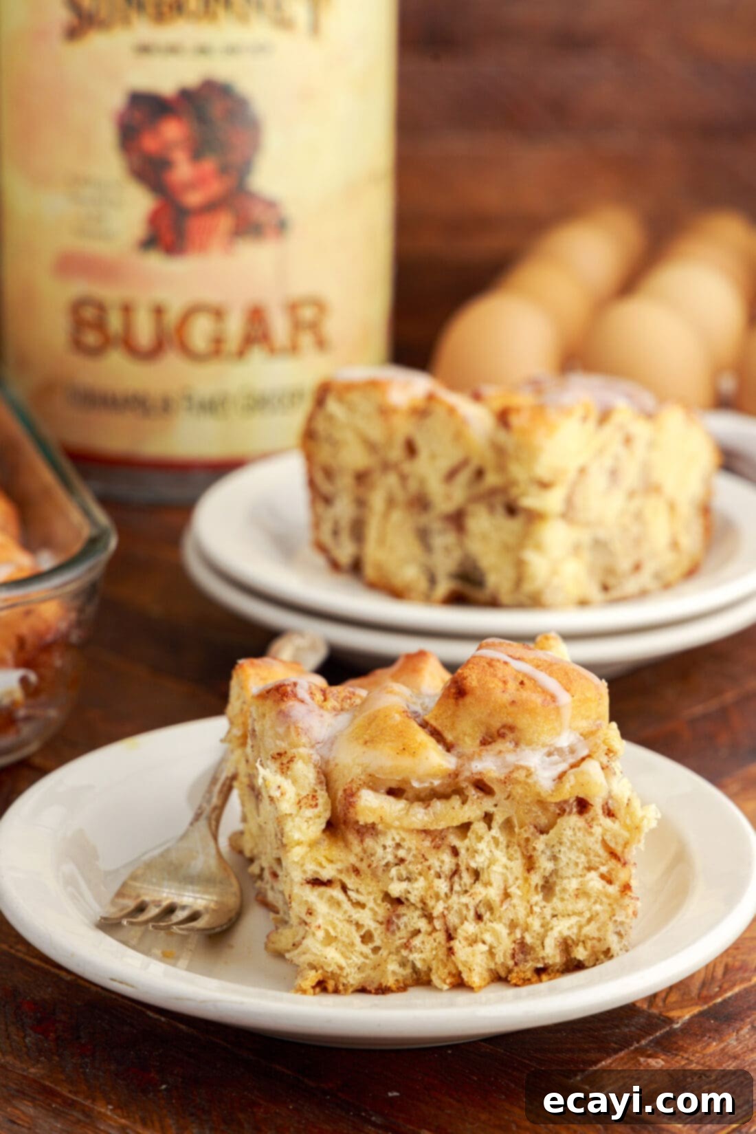 Gooey Cinnamon Brunch Bake 12 Serving of Cinnamon Roll Casserole on a plate, garnished with a light dusting of cinnamon