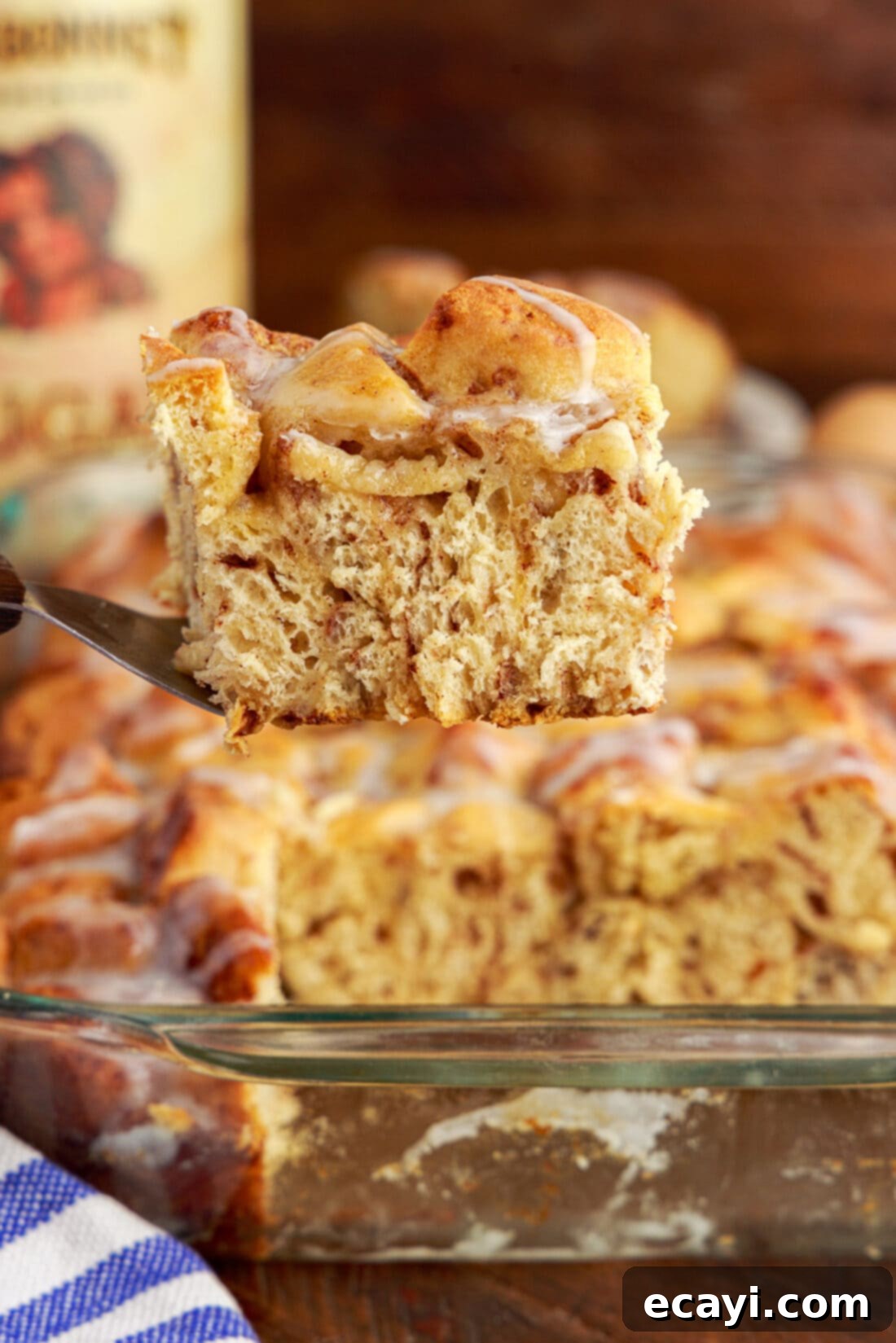 Gooey Cinnamon Brunch Bake 3 Serving of Cinnamon Roll Casserole being lifted out of the pan with a spatula, highlighting its soft texture