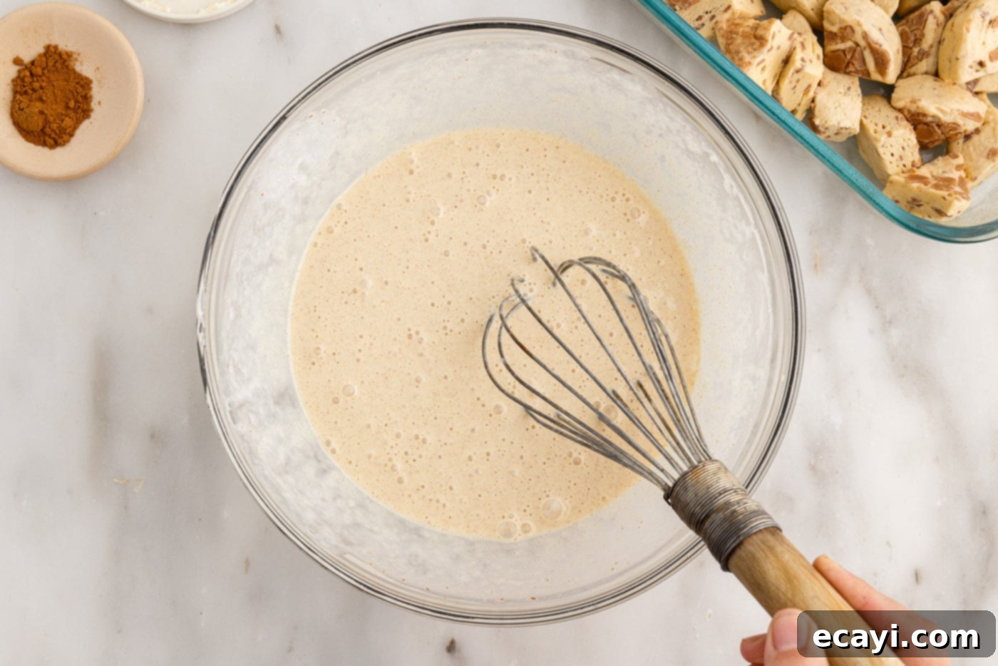 Gooey Cinnamon Brunch Bake 7 cinnamon roll custard filling ingredients in a bowl with a whisk
