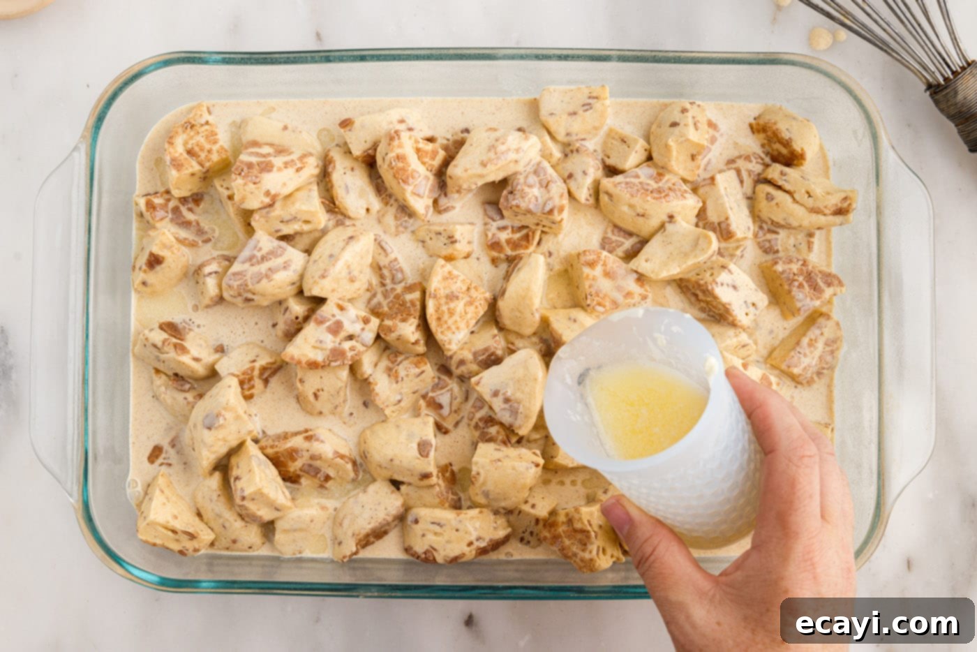 Gooey Cinnamon Brunch Bake 9 pouring melted butter over cinnamon roll ingredients in a baking dish
