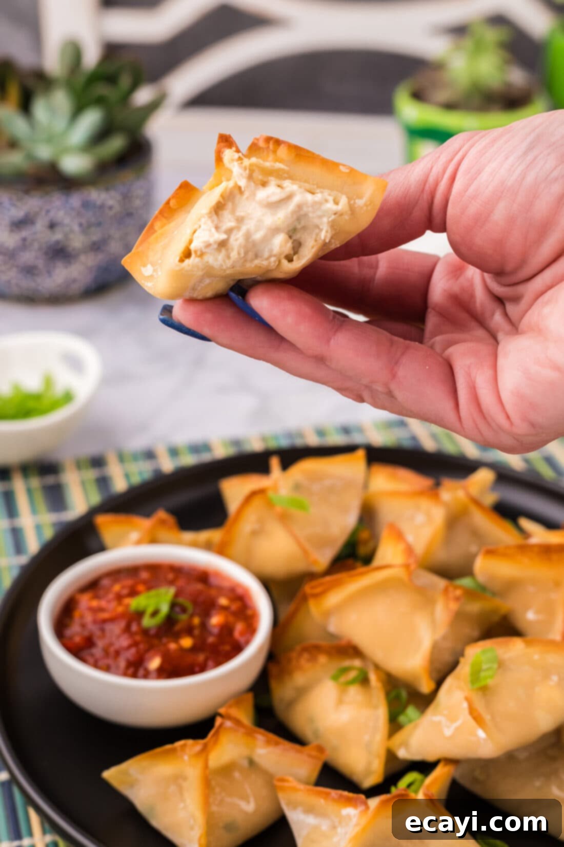 Golden Crab Cream Crisps 2 Hand holding up half of a Crab Rangoon showing the inside filling
