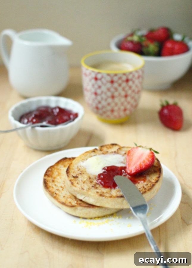 Bake Your Own Whole Wheat English Muffins 3 Freshly baked whole wheat English muffins cooling on a rack, showcasing their golden-brown tops and sides.