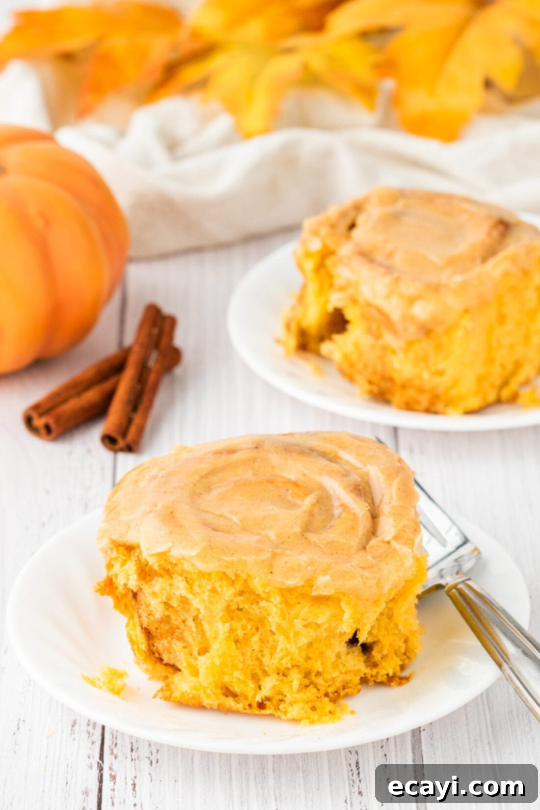 Golden Pumpkin Spiced Swirls 2 Two Pumpkin Cinnamon Rolls on plates, perfectly frosted and ready to eat