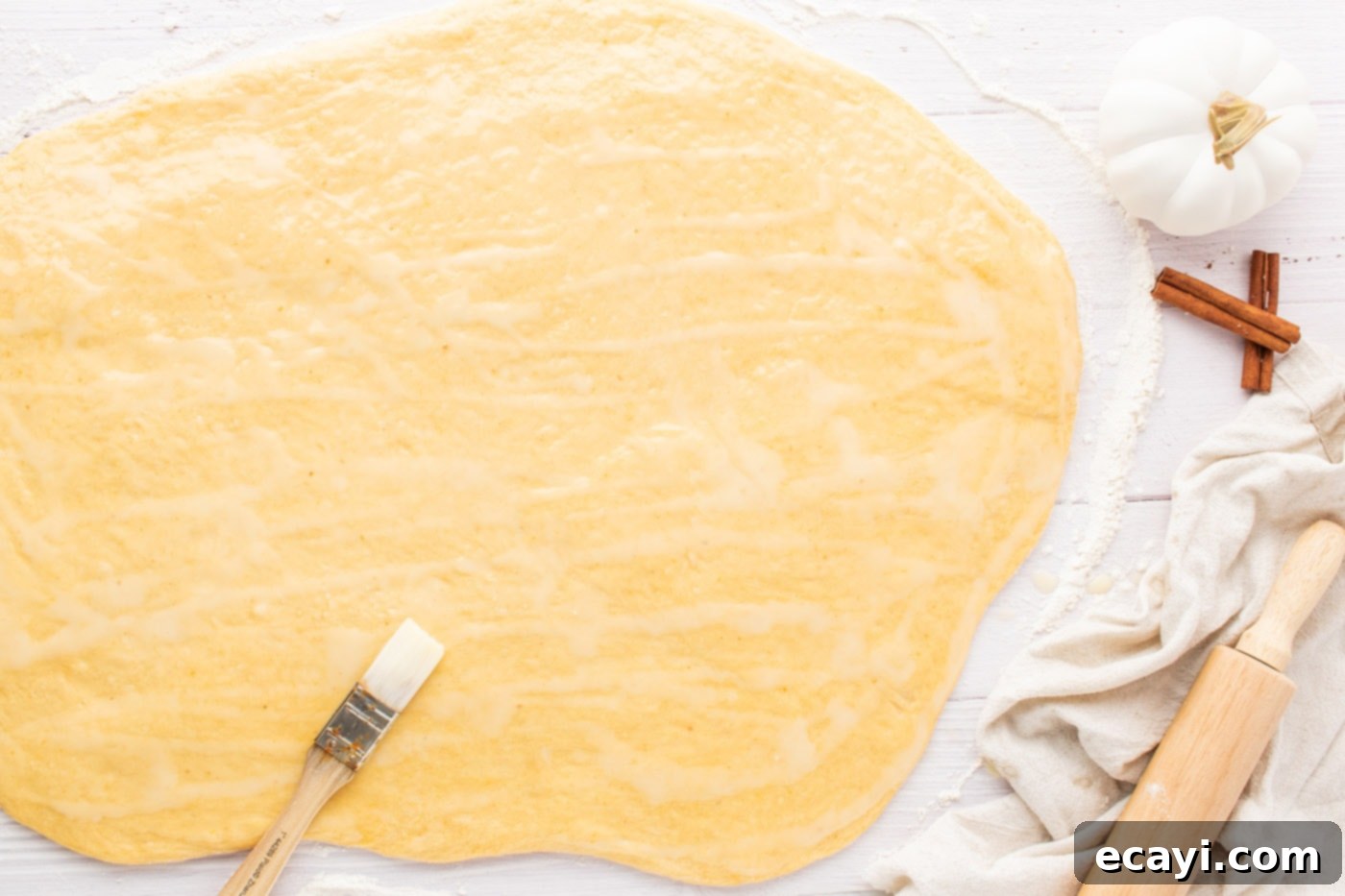 Golden Pumpkin Spiced Swirls 11 spreading butter over pumpkin cinnamon roll dough