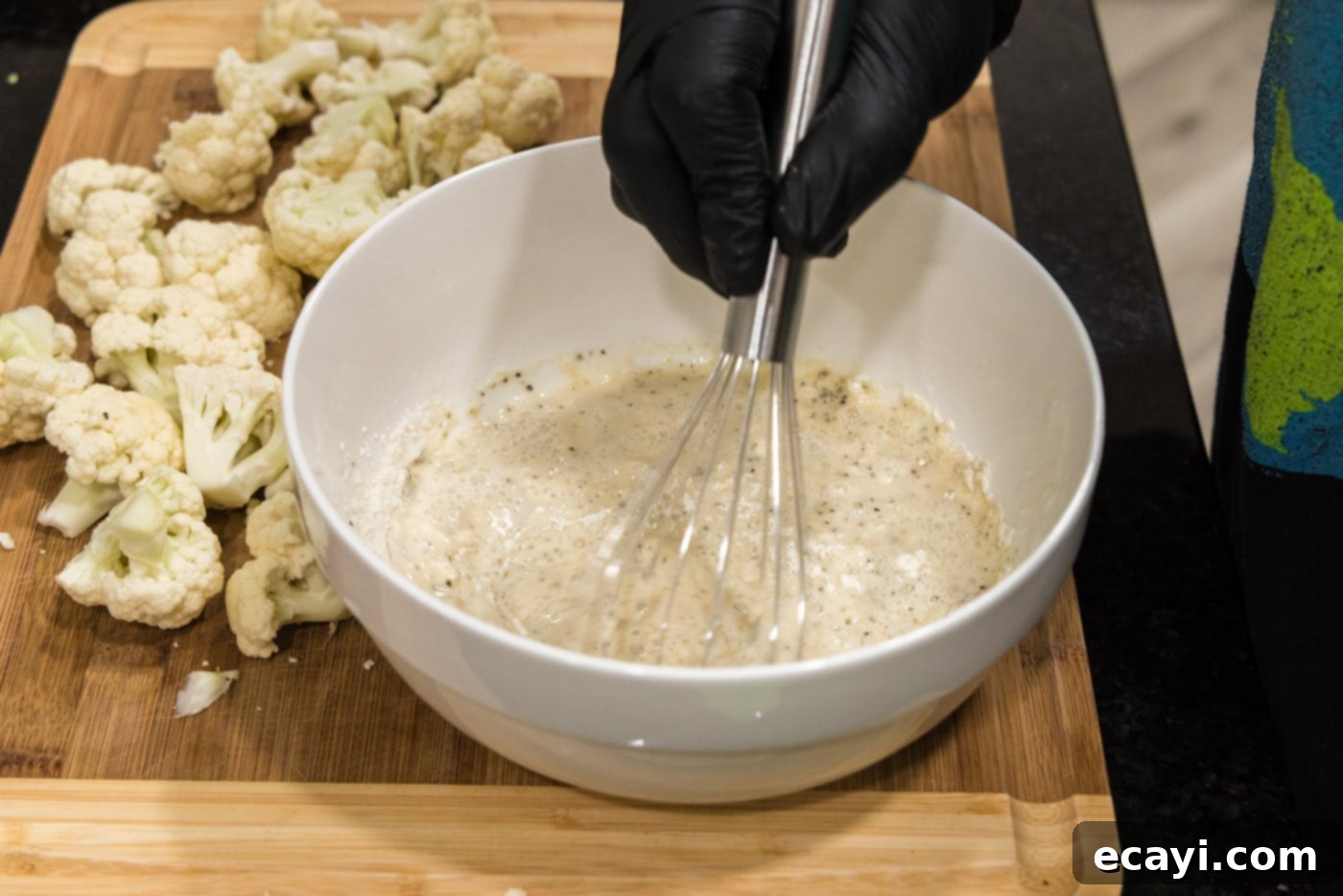 Buffalo Cauliflower Bites 8 whisking flour, water, and seasoning in a bowl