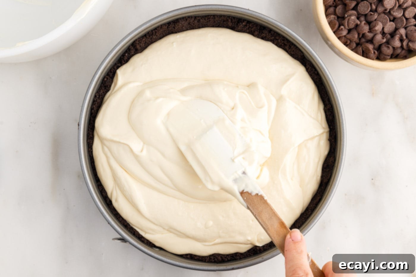 Irresistible Baileys Cheesecake 12 spreading cheesecake filling on top of Oreo crust
