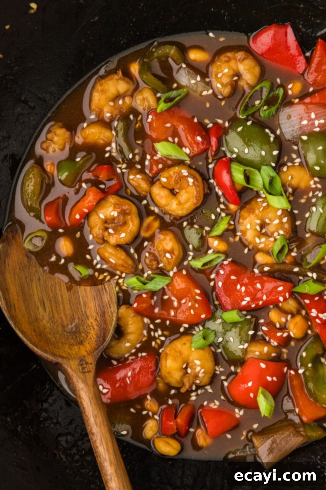 Fiery Wok Shrimp 3 Close up photo of a wok of Kung Pao Shrimp with a spoon in it, showcasing the rich sauce and ingredients