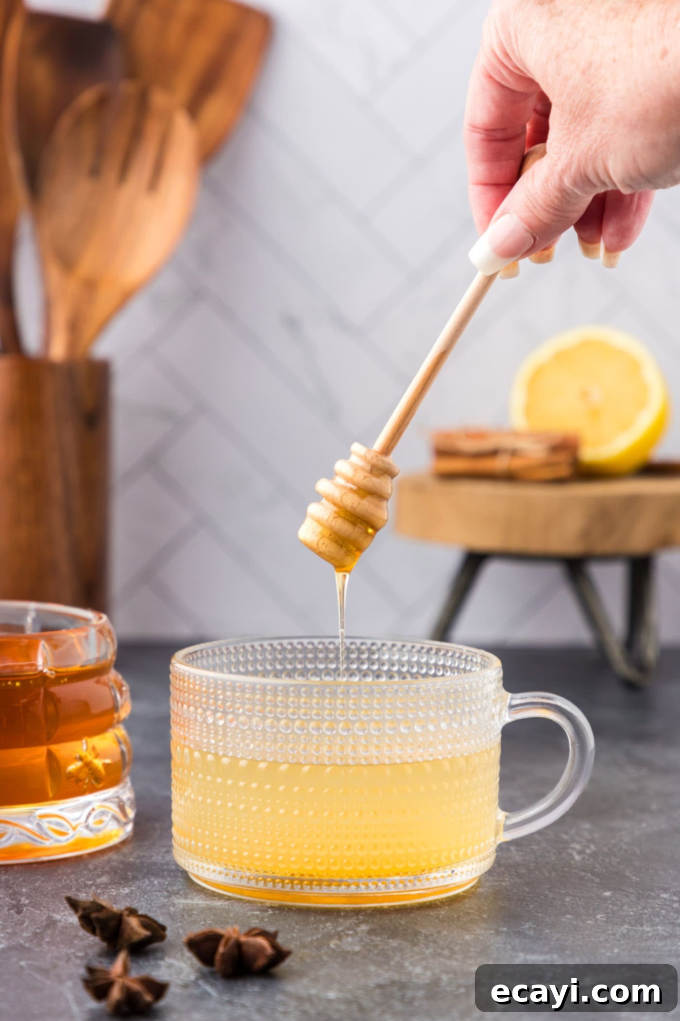 Cozy Comfort Brew 7 adding honey to glass with whiskey, water, and lemon juice