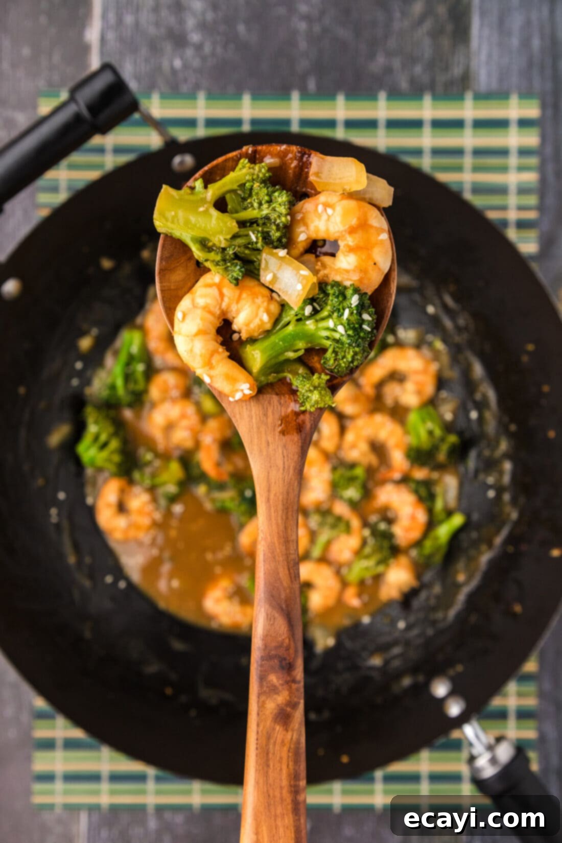 Garlic Shrimp & Broccoli Sauté 3 Spoon of Shrimp and Broccoli held above a wok of Shrimp and Broccoli, showcasing the rich sauce