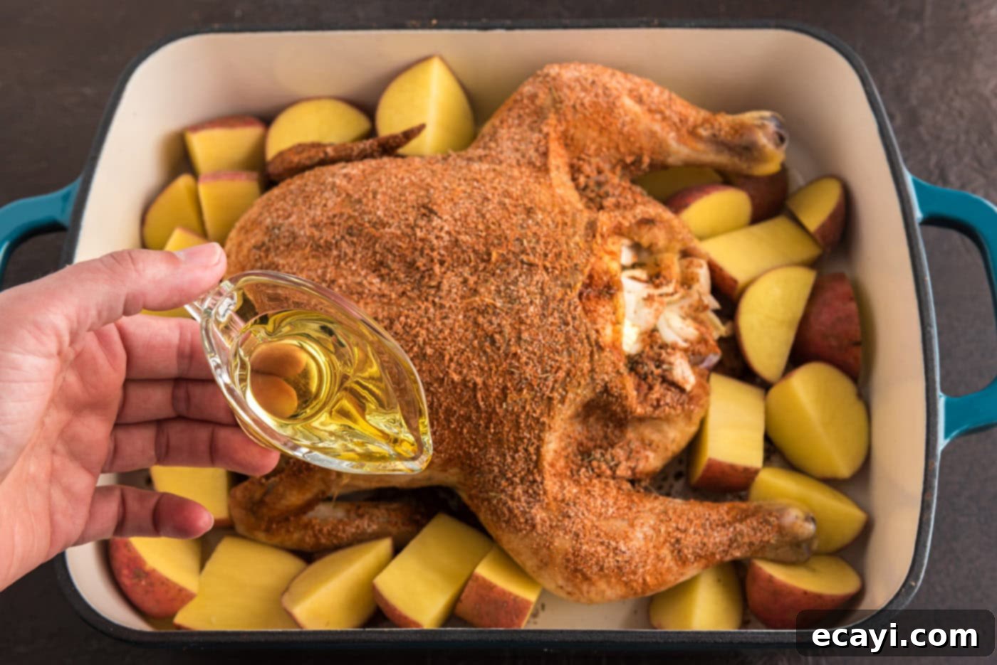 Slow Roasted Caramelized Chicken 7 pouring olive oil into pan with whole chicken and red potatoes