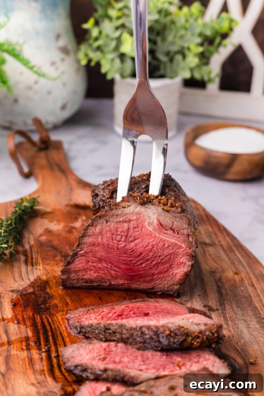 Perfect Air Fryer Roast Beef 2 A carving fork gently holding a slice of perfectly cooked Air Fryer Roast Beef on a rustic wooden cutting board, highlighting its juicy texture and ideal doneness.