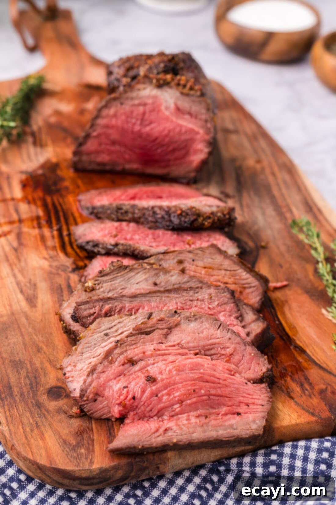 Perfect Air Fryer Roast Beef 3 Several glistening slices of Air Fryer Roast Beef are neatly arranged on a wooden cutting board, showcasing their tender, pink centers and inviting aroma.