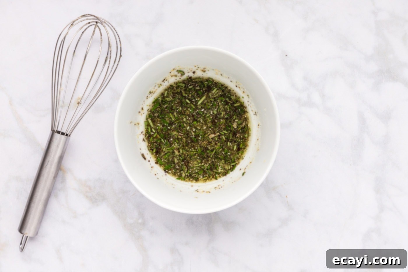 Perfect Air Fryer Roast Beef 6 The blended mixture of olive oil, fresh rosemary, and other seasonings in a bowl, forming a thick, fragrant paste ready for application.