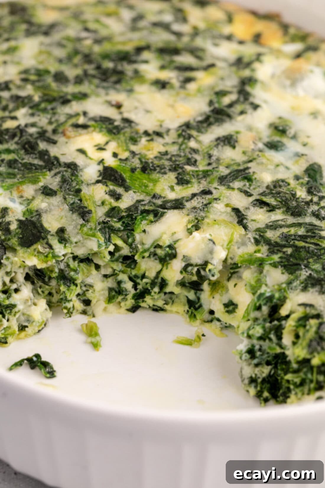 Savory Spinach Cloud 11 A close-up view of a baked spinach souffle with a portion neatly removed, revealing its creamy, cheesy, and green interior, ready for serving.