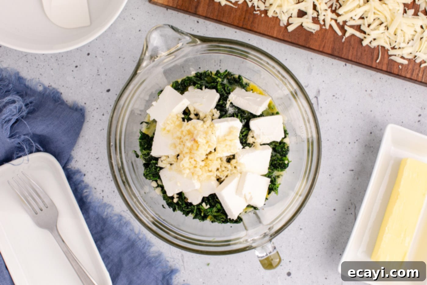 Savory Spinach Cloud 6 Cubed cream cheese, minced garlic, and shredded pepper jack cheese being added to a bowl with spinach and eggs, showcasing the fresh ingredients.