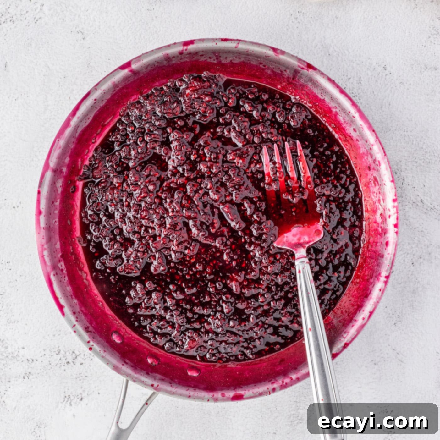Blackberry Swirl Cheesecake 6 blackberry reduction with a fork in a saucepan