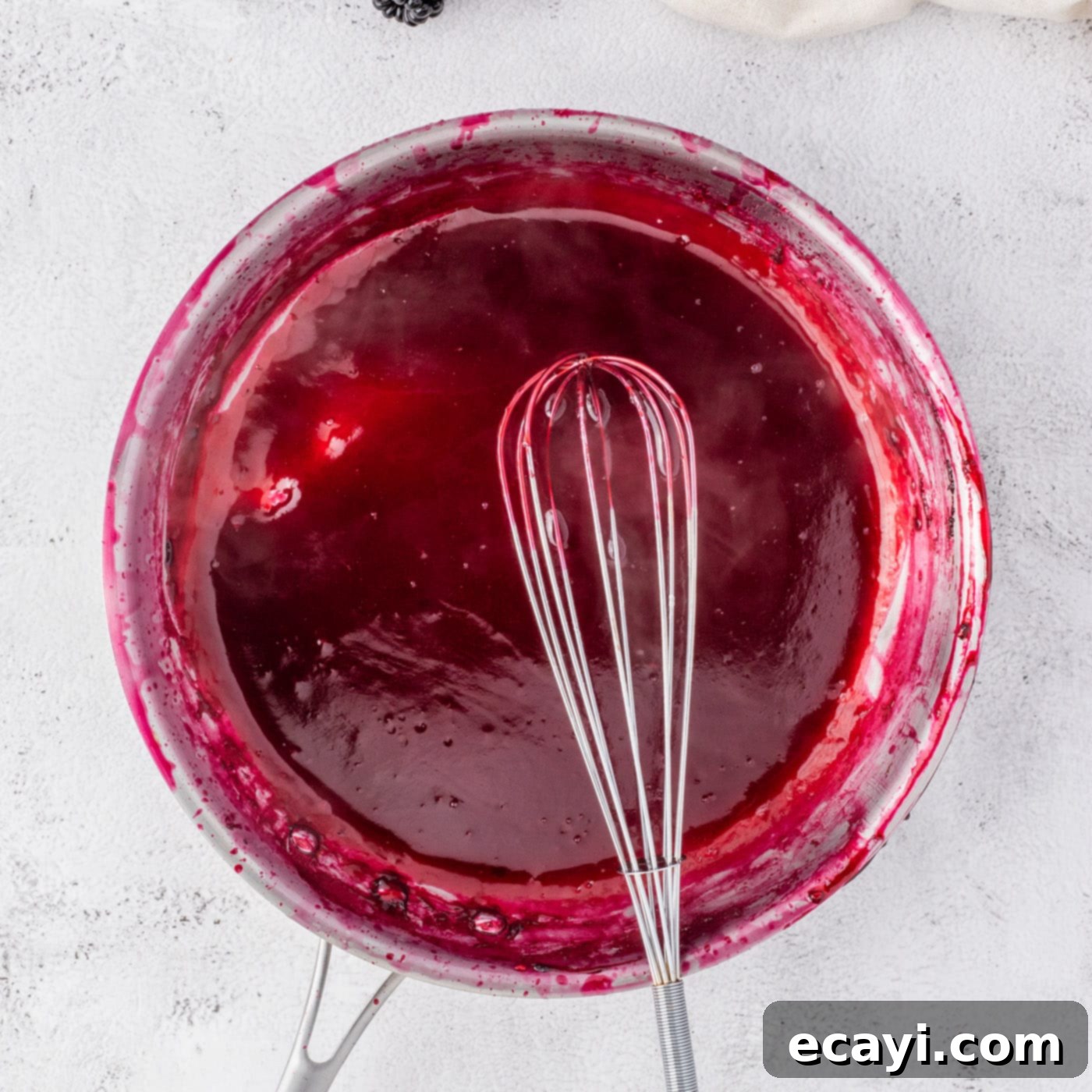 Blackberry Swirl Cheesecake 7 whisking blackberry reduction in a bowl