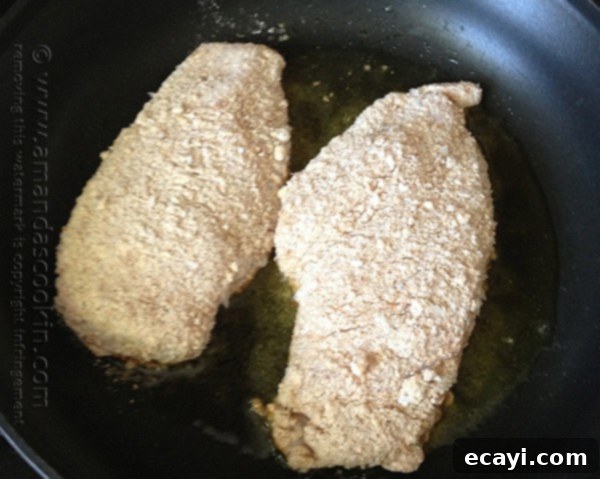Golden-Crisp Oven Chicken Breasts 10 Two chicken breasts, beautifully covered in a crumb coating, sizzling gently in olive oil in a skillet.
